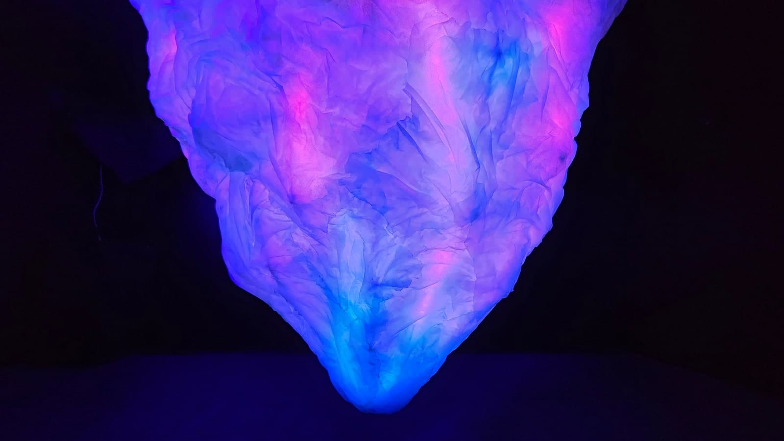 The hanging iceberg glowing blue and pink against the dark exhibition room.